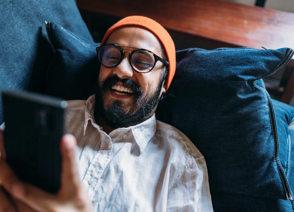 Man with a call phone laying on a sofa