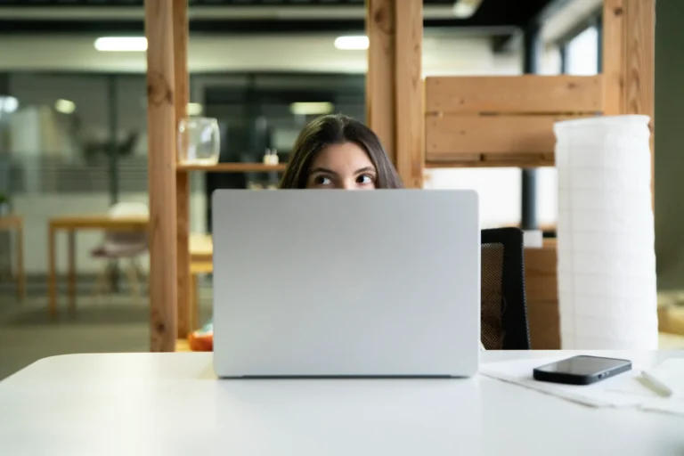 Woman peeking above laptop while working on AI product demo