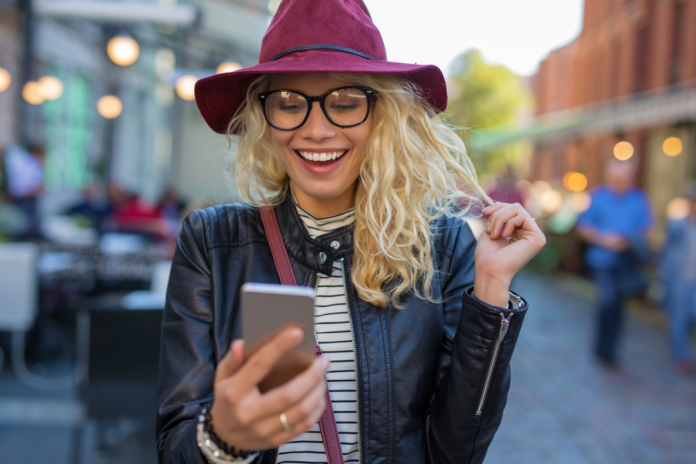 consumer looking at customer experience marketing on phone and smiling